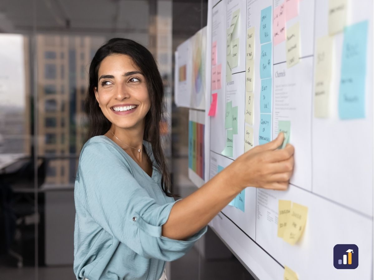 Smiling CX professional adding sticky notes to a customer journey map on a wall